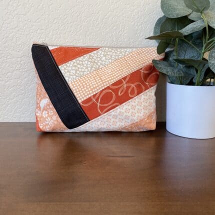 A quilted patchwork zipper pouch in orange and black tones.