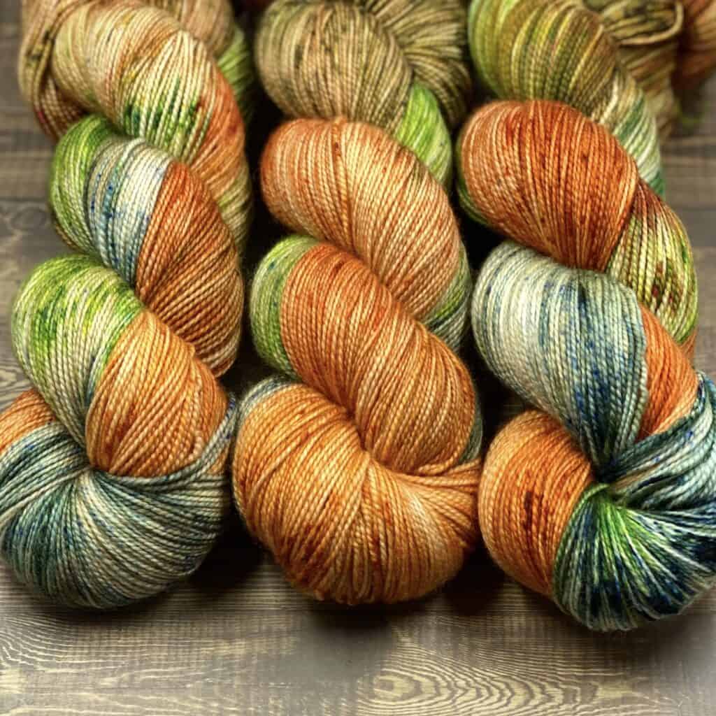 Three skeins of orange, green and blue multicolored yarn.