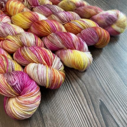 Skeins of yarn in yellow, bright pink and dusty pink.