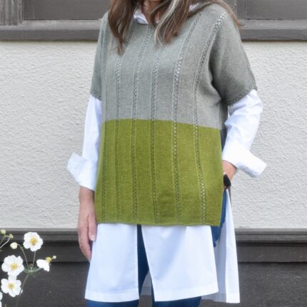 The front view of a short-sleeved sweater with a long open vent at the sides knit in gray, mossy green and dark gray. It is worn over a long button-down white blouse.