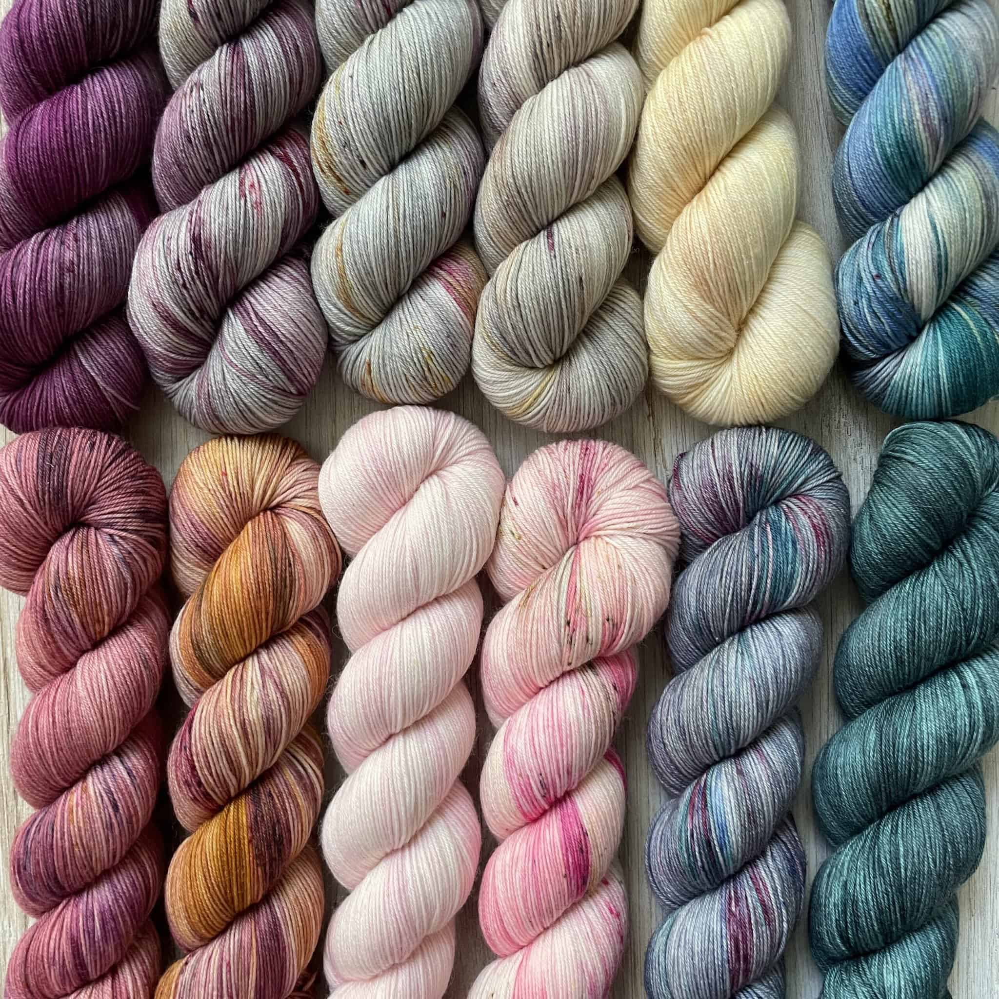Skeins of purple, gray, yellow, blue, pink and orange yarn.