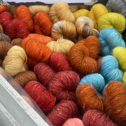 A box of skeins of yarn in shades of red, orange, brown and yellow.