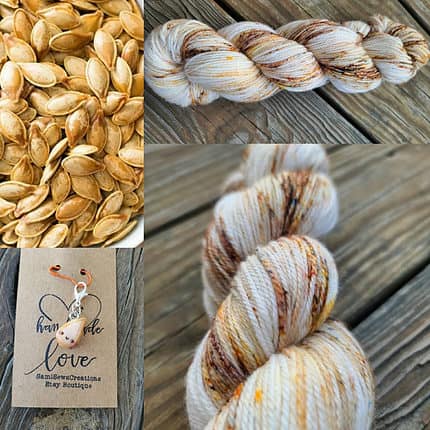 A white skein of yarn lightly speckled with orange and browns and a toasted pumpkin seed charm.