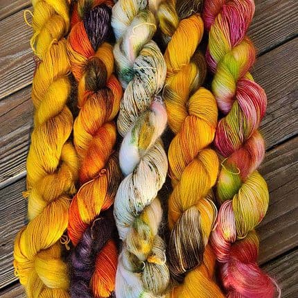 Skeins of yarn in apple red, sunflower yellow and pumpkin oranges.