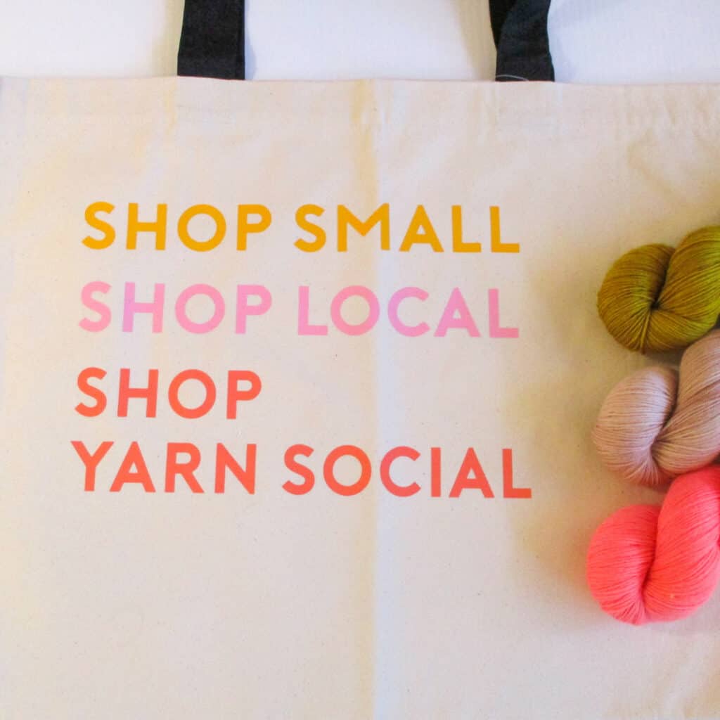 A cotton tote bag that reads Shop Small, Shop Local, Shop Yarn Social.