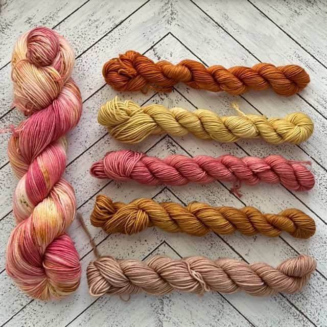 1 large pink skein and 5 small skeins in various pinks and neutral colors.