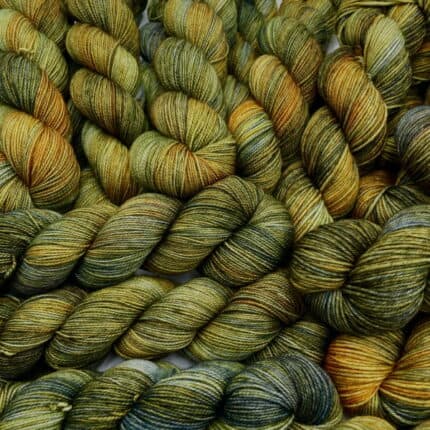 A pile of green and gold skeins of yarn.