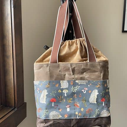 A large beige waxed canvas bag with hedgehog and mushroom fabric.