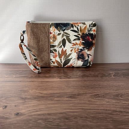 A wristlet zipper pouch with a floral print in brown tones.