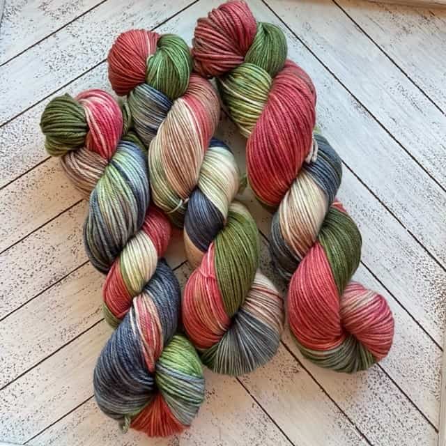 Three skeins of yarn in red, green, blue, and brown.