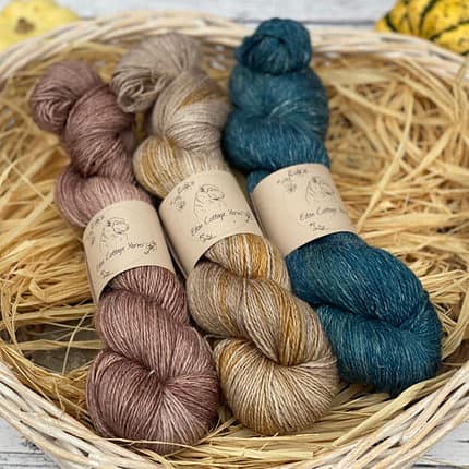 Three skeins of yarn in shades of brown and blue.