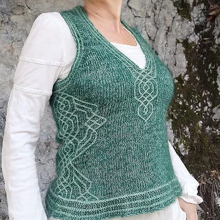A light-skinned woman wearing a green cabled vest.