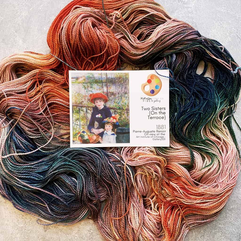 A skein of orange, blue and green multicolored yarn and an art card.