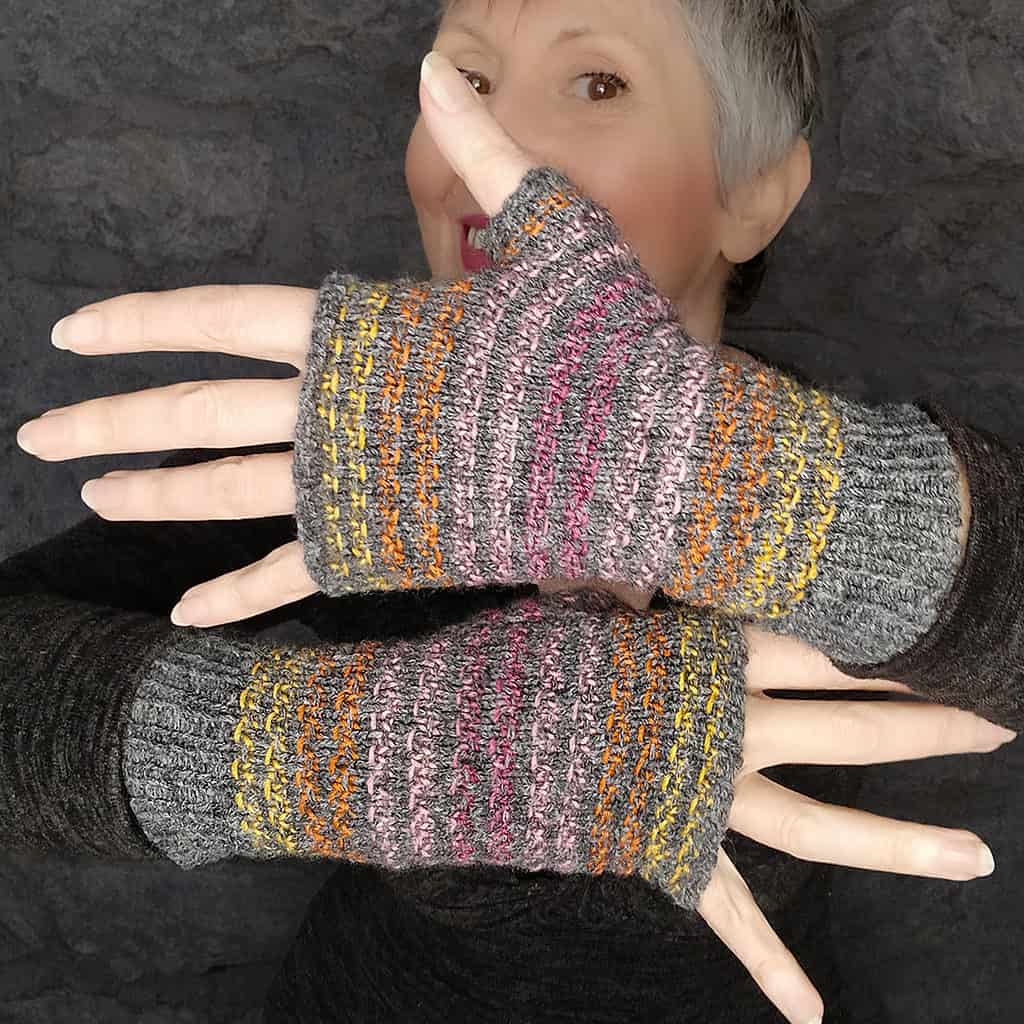 Fingerless mitts in gray with yellow, orange, pink and purple stripes.
