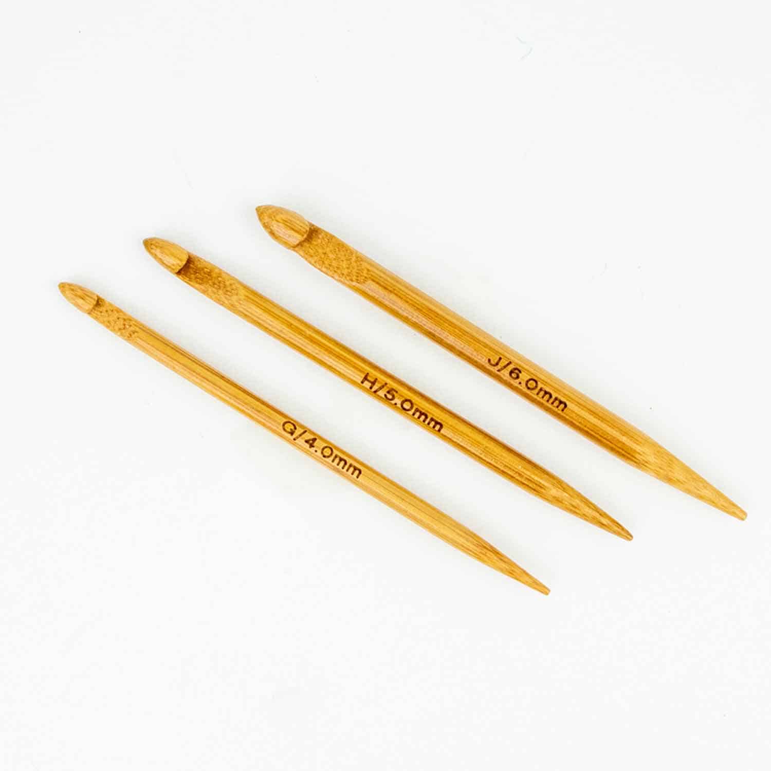 Three small wooden crochet hooks on a white background.