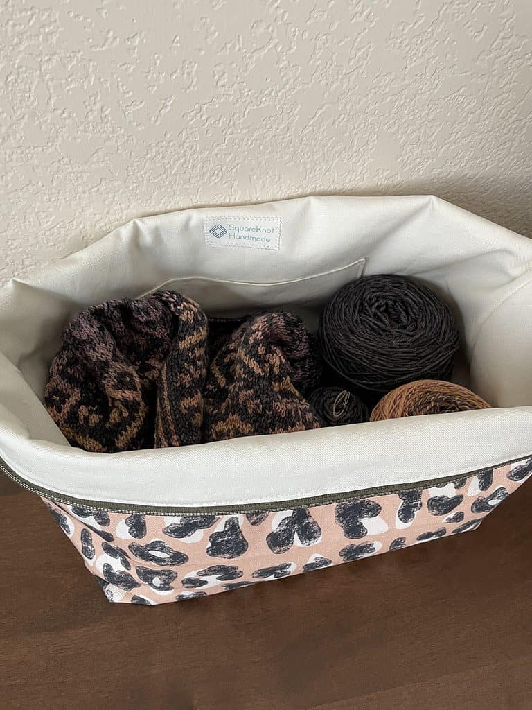 Overhead picture of a project bag filled with yarn and WIP, exterior of bag has leopard print fabric.