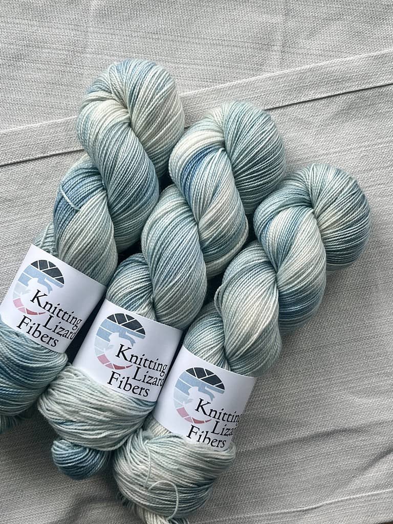 Hoarfrost on BFL Twist. Light blue variegated colors of yarn on a cream background.