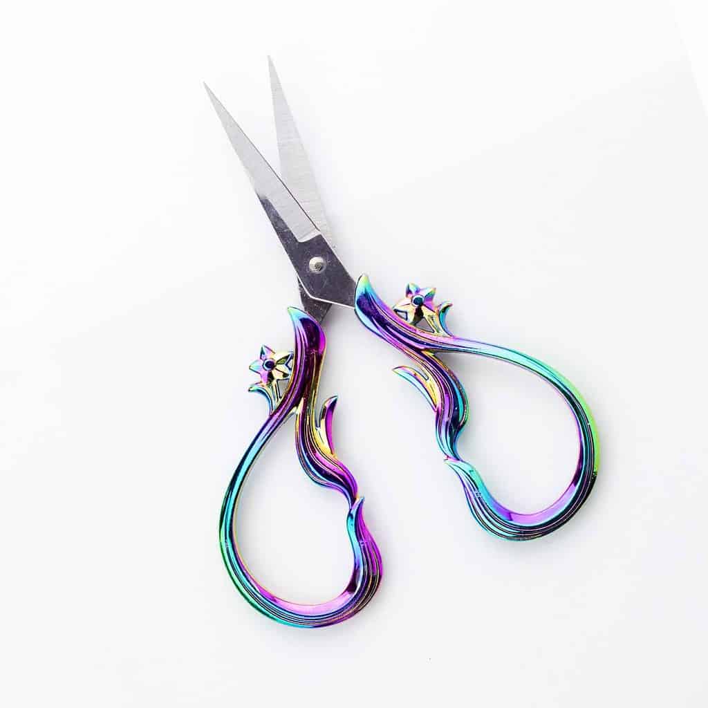 Shiny teal and purple open scissors with silver blades.