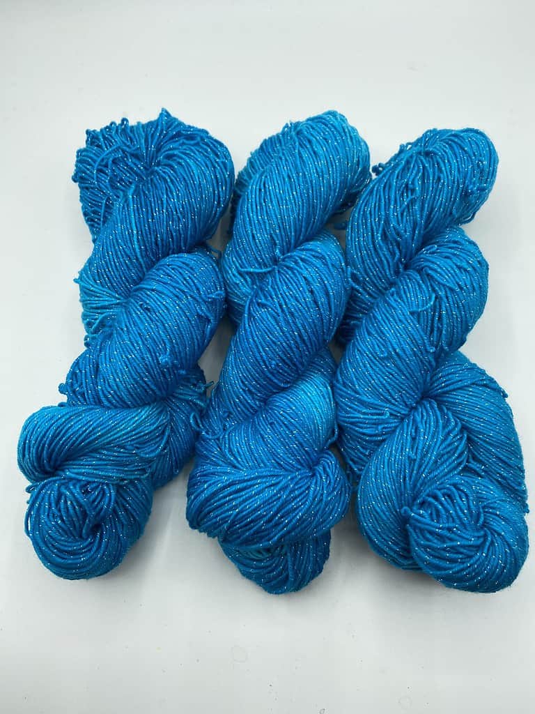 Three skeins of medium turquoise yarn with sparkle.