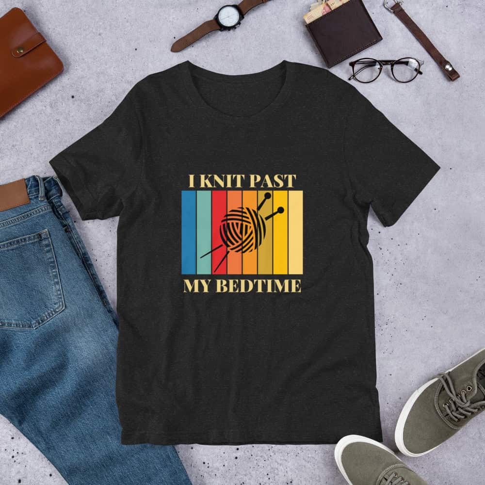 A black t-shirt that says I knit past my bedtime, with a black yarn ball and knitting needles over a rectangle of rainbow colors.