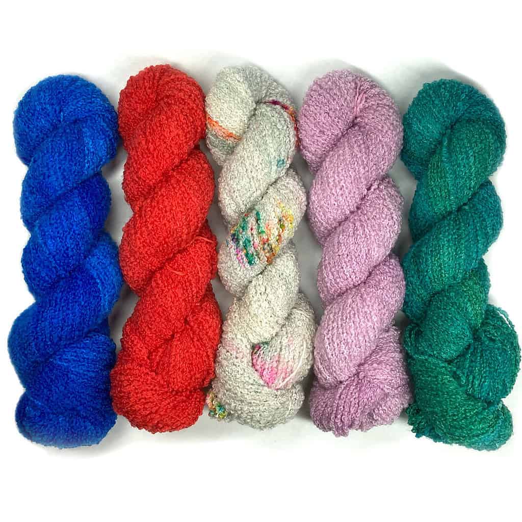 Blue, red, gray, pink and teal boucle DK-weight yarn.