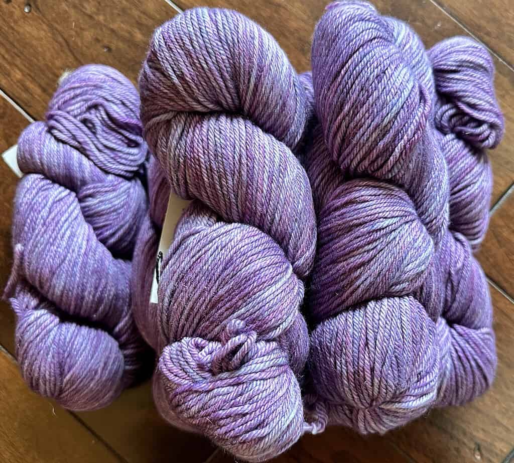 Skeins of light purple tonal worsted weight yarn.