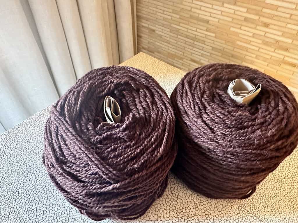 Two skeins of brown yarn in yarn cakes.