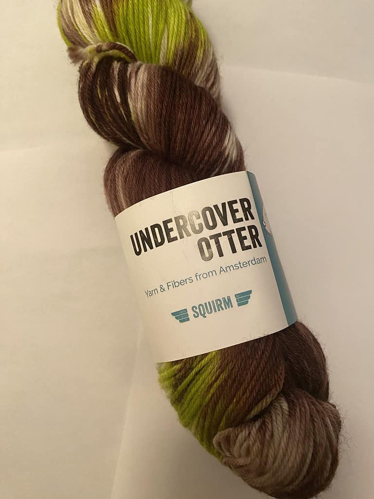 A skein of variegated bright green, brown and white yarn.