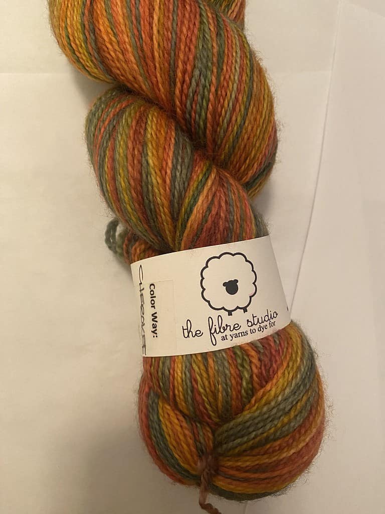 A skein of multi-color yarn in fall colors of yellow, orange, green and brown.