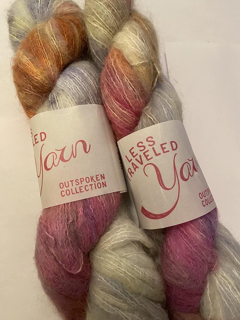 Two skeins of fuzzy purple, gray and orange variegated yarn.