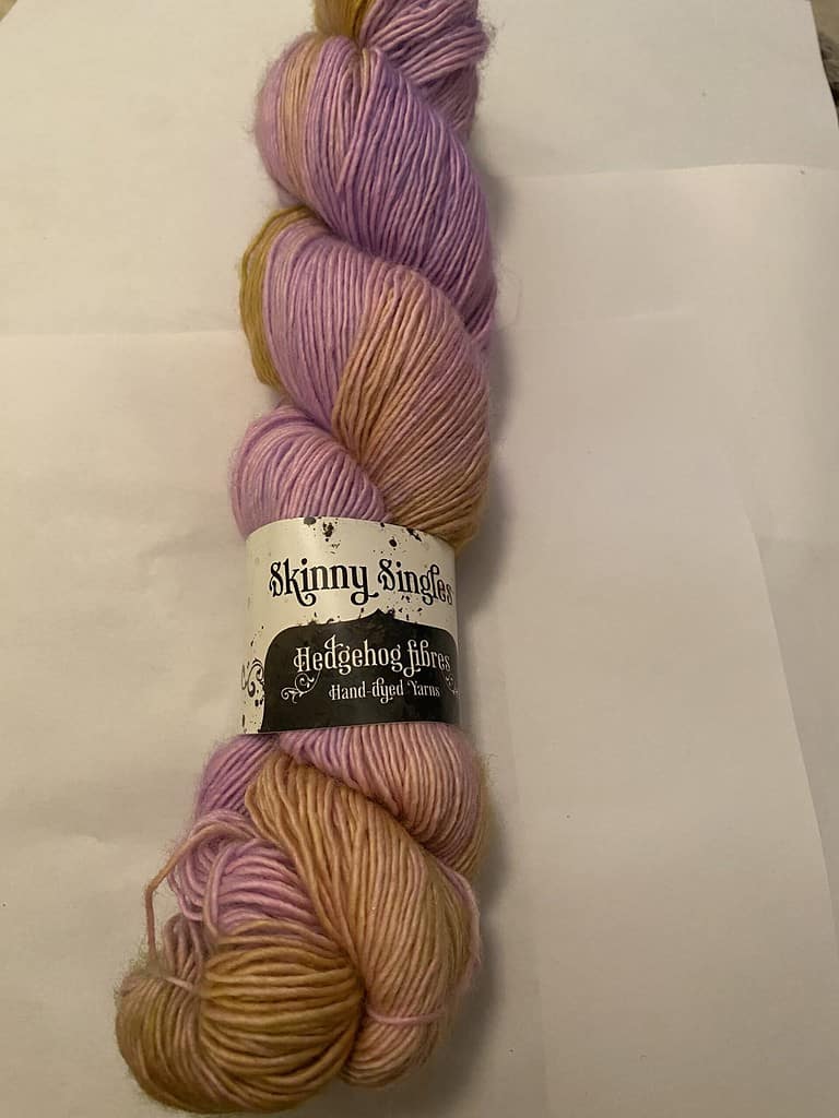 A skein of purple and yellow variegated single-ply yarn.