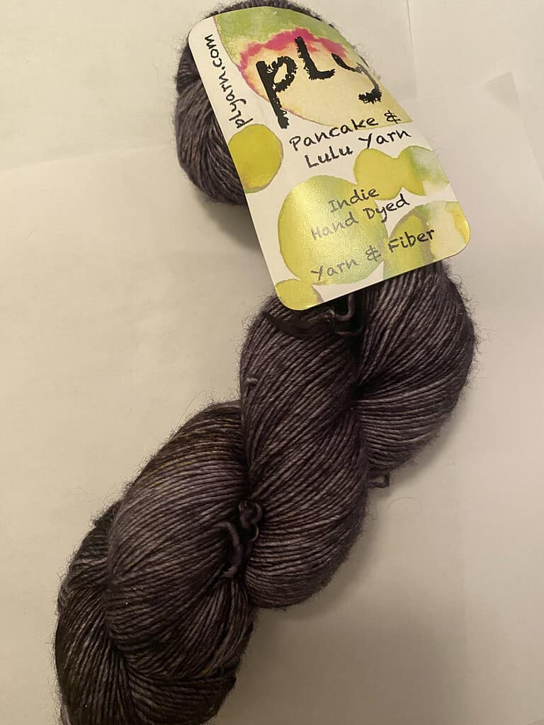 A skein of dark gray single-ply fingering weight yarn.