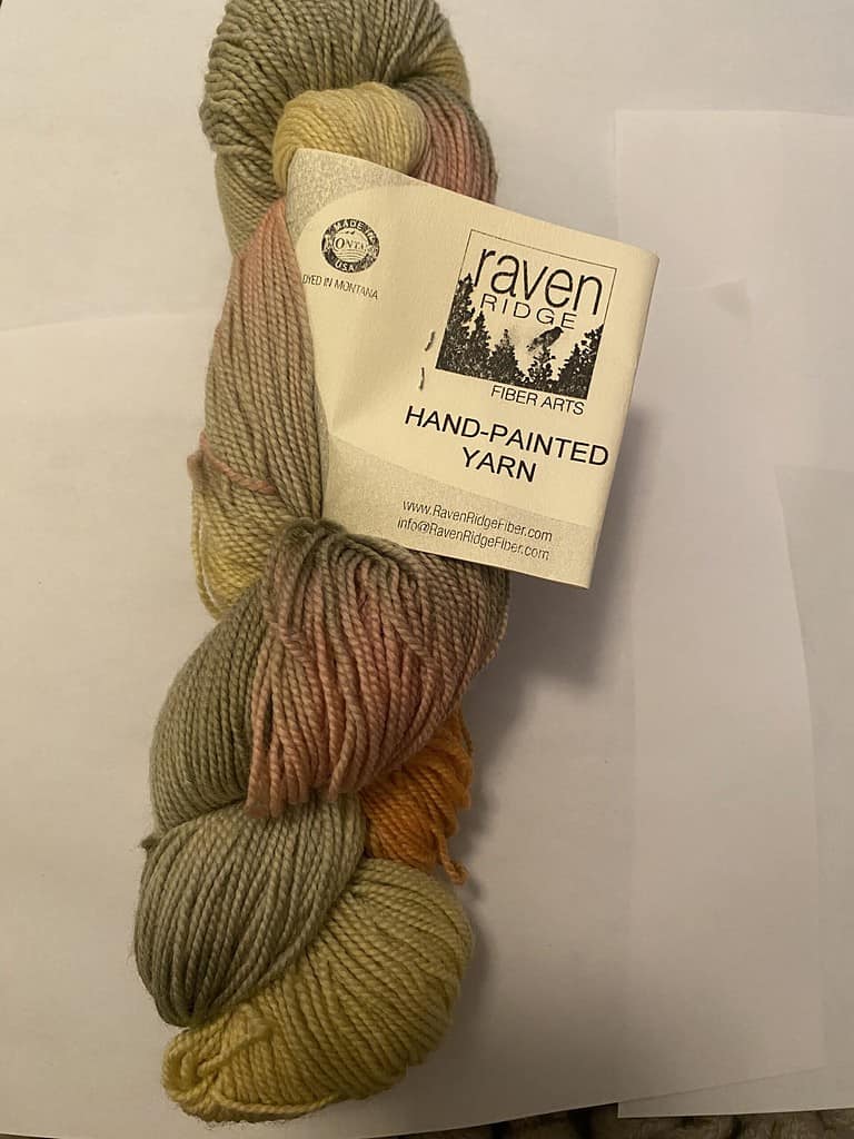 A skein of pink, gray and yellow variegated yarn.