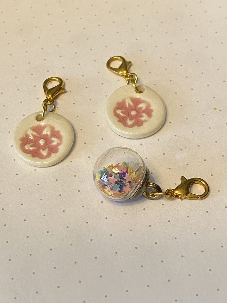 Set of 3 ceramic floral and glass with rainbow stars stitch markers.