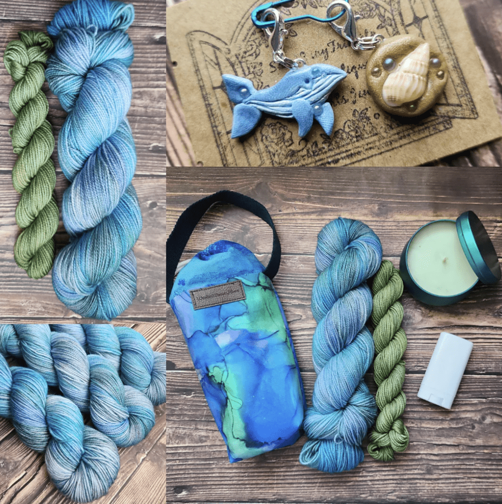 Blue, Purple, and green variegated yarn with a green mini skein next to an ocean colored water bottle holder with a black strap, whale and seashell themed charms, a candle and a lanolin lotion bar.