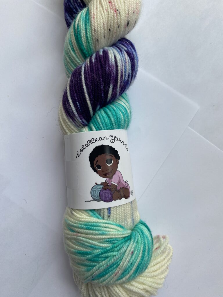One skein variegated and speckled yarn in neutral, aqua and purple.