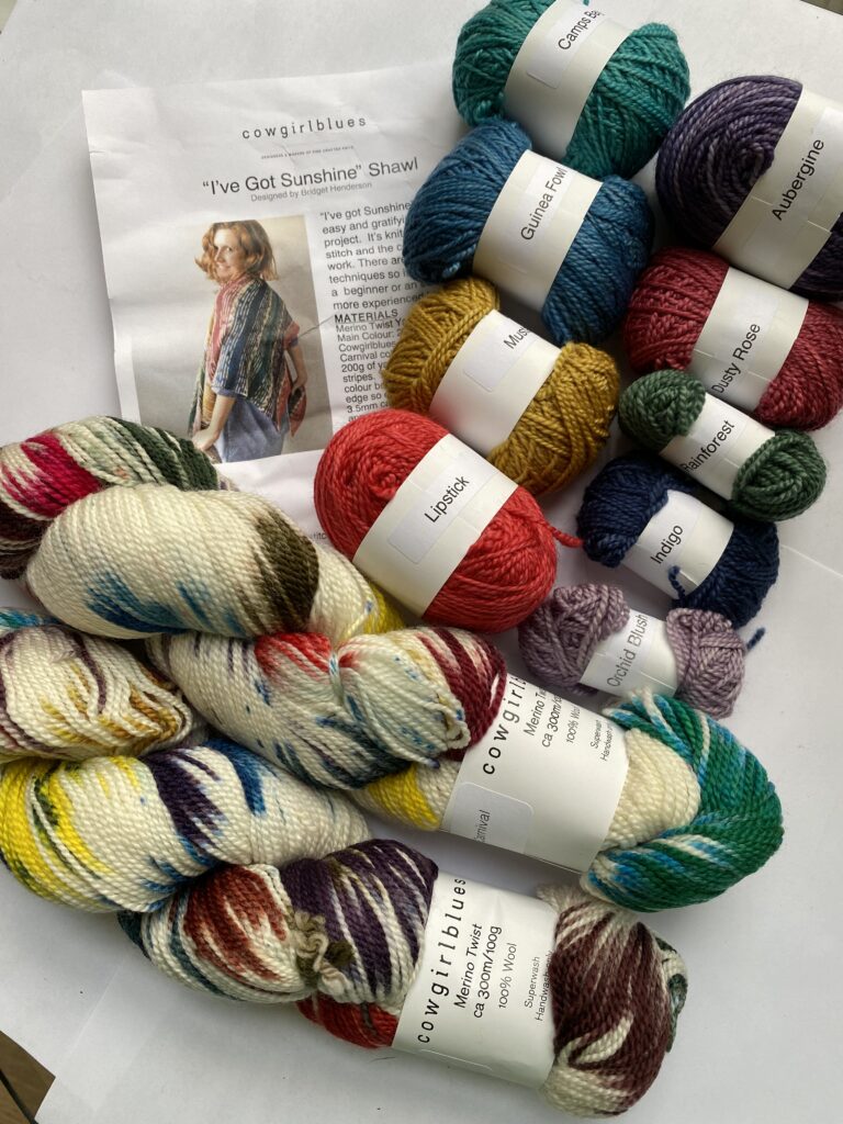 2 full skeins neutral, purple, blue and red yarn. 9 mini skeins in various colors and shawl pattern.