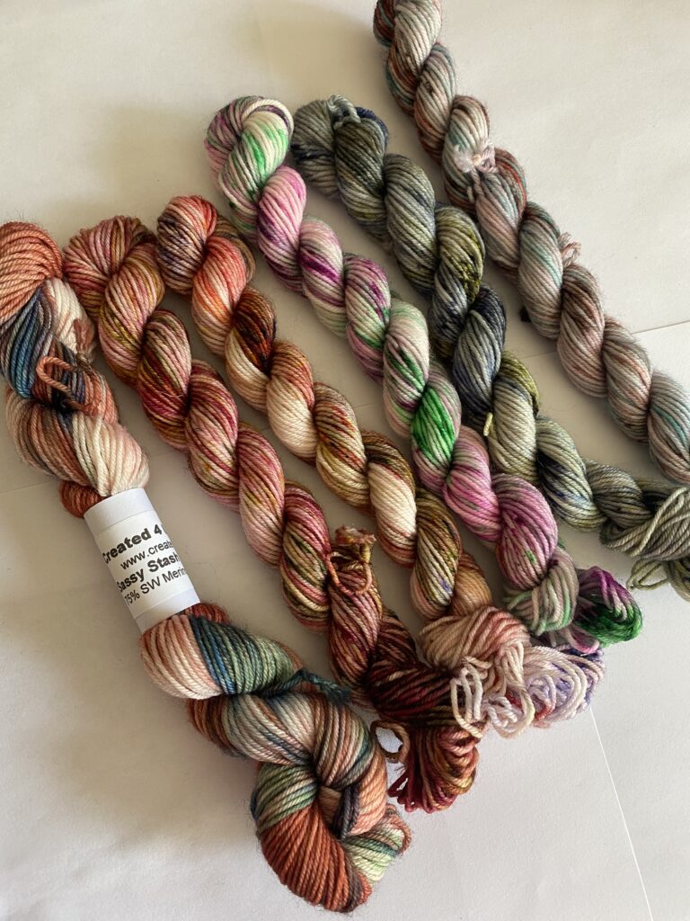 6 mini skeins of pink, green, blue and gray yarn.