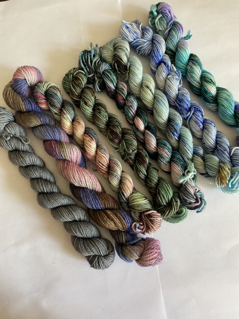8 mini skeins of blue, green and pink yarn.