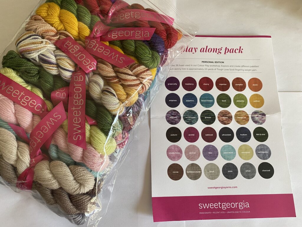 Multiple mini skeins in a variety of different colors in a clear bag and a card with circles of colors.