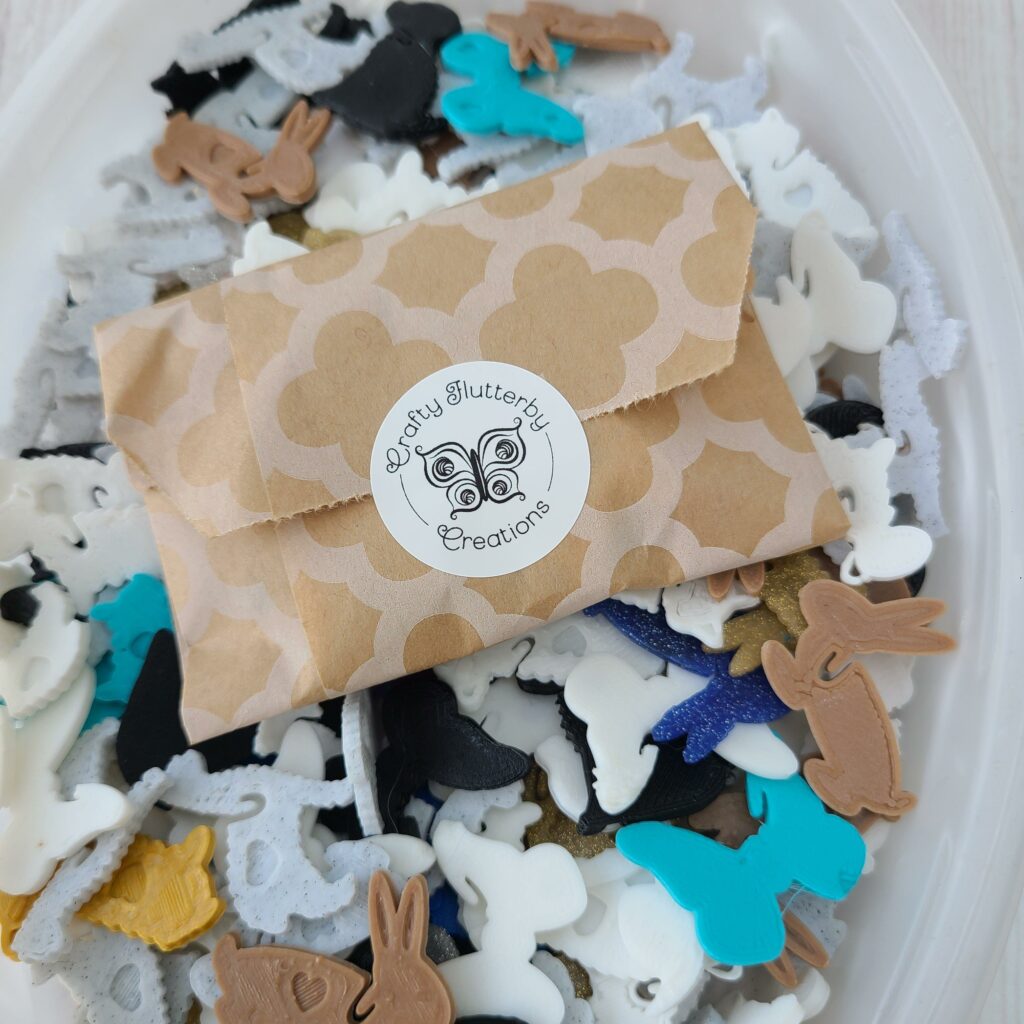 A bag with sticker on a pile of plastic in animal shapes in various shades of white, black, blue, brown and yellow.