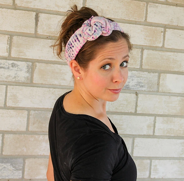 A white woman wearing a light pink and white knit headband.