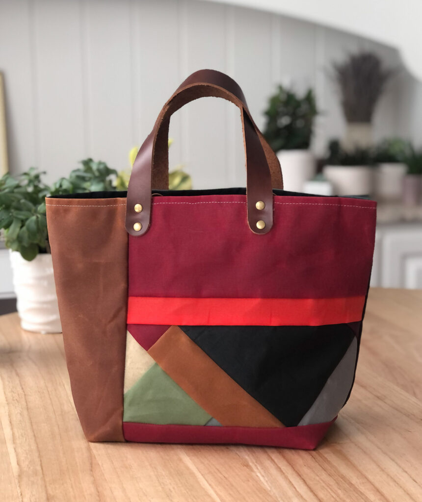 A multicolored bag with brown, maroon, orange, black, green and gray panels of fabric.