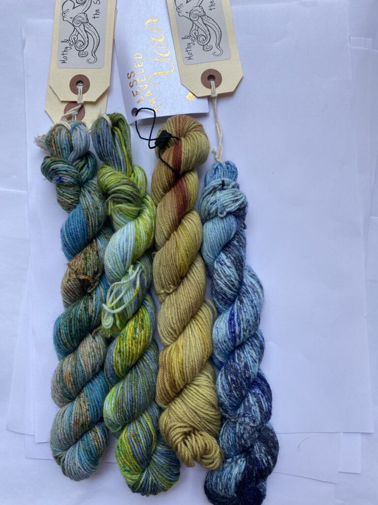 4 mini skeins of green, blue and brown yarn.