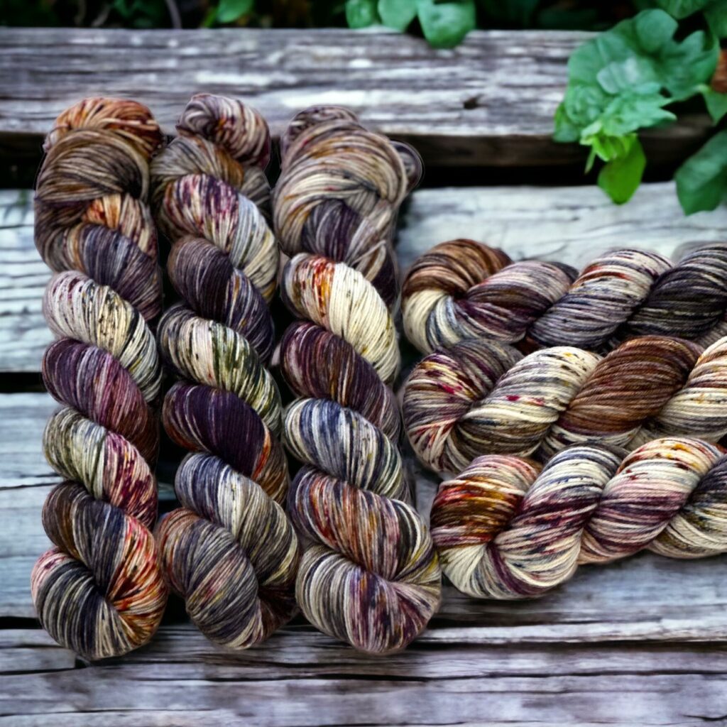 Gray, purple, brown and blue skeins of yarn on a wooden background.