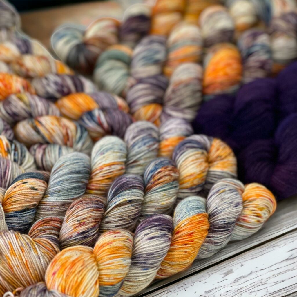 Many hanks of variegated orange, purple, teal yarn called Harvest Moon.