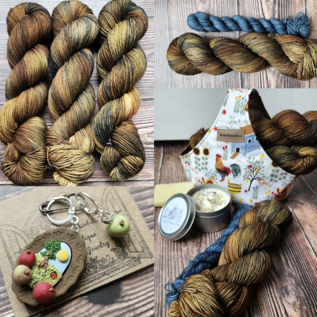 Variegated brown and slate blue yarn with a slate blue mini skein, yarn in a chicken coop autumn themed fabric basket and a pendent charm with apples fallen from an apple tree. A candle, soap bar and basket sits aside a sock set in like colors.