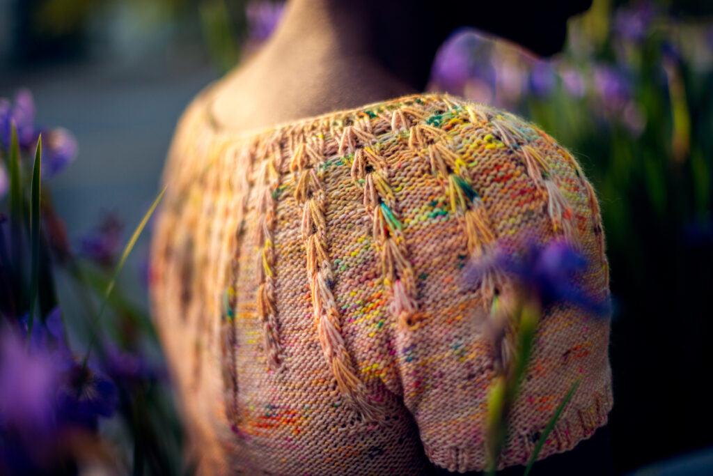 The shoulder of an orange speckled knit sweater.