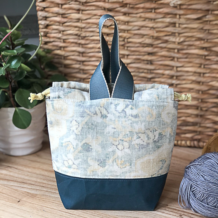 A small blue and cream project bag standing on a table.