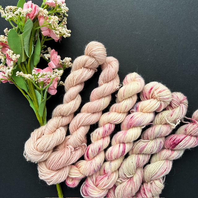 Row of pink spackled yarns, with pink flower bouquet.